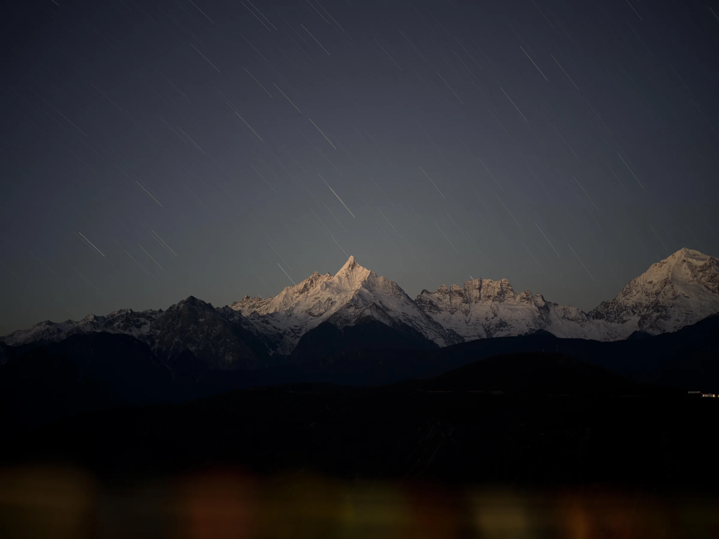 云南滇西北夜色中的星轨、雪峰与灯光