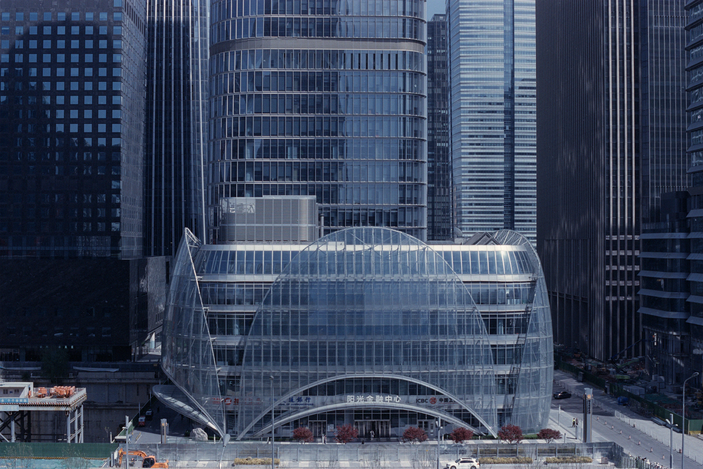 多座高楼之间，一座弧形玻璃建筑位于画面中央