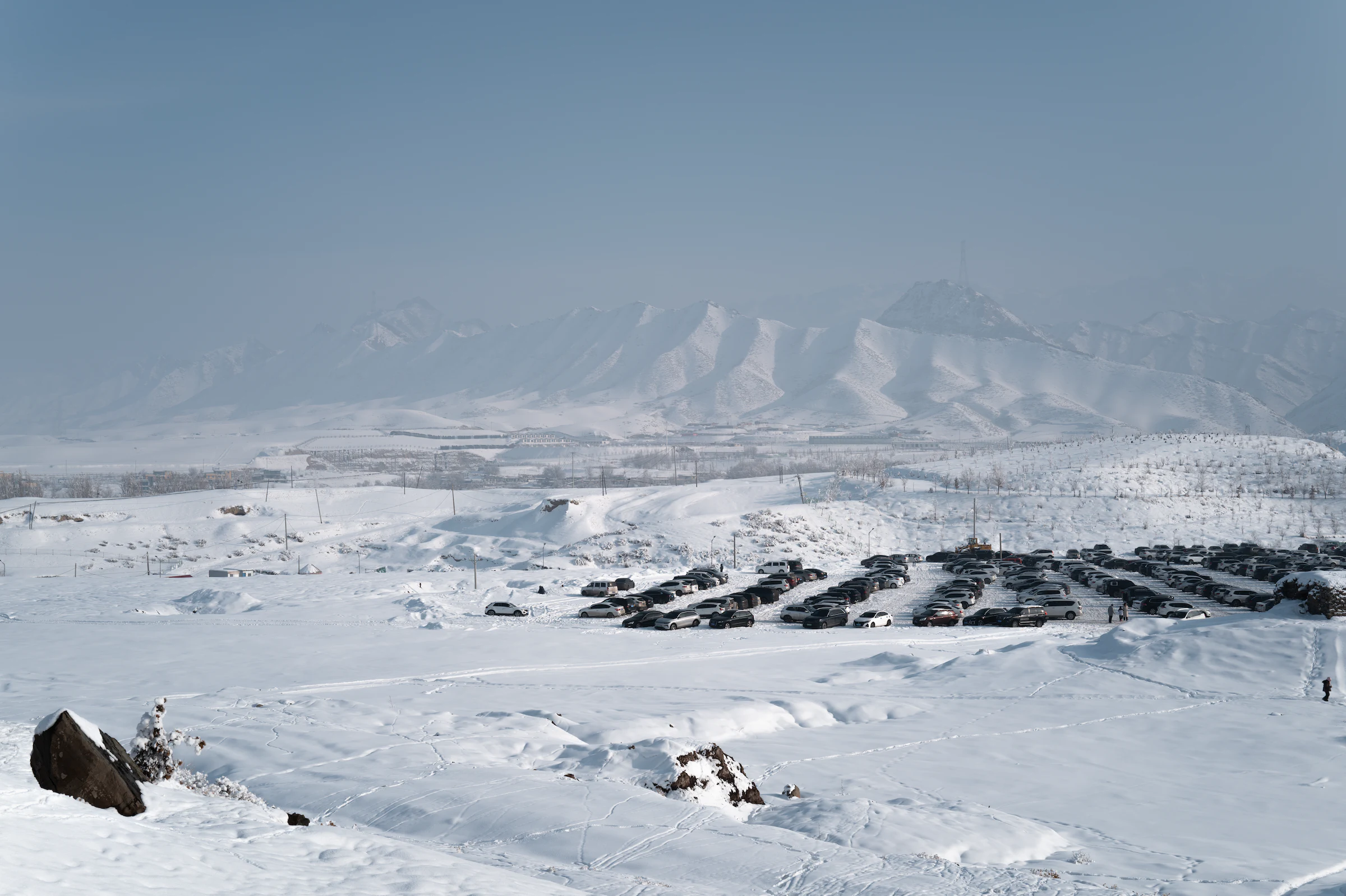 新疆乌鲁木齐的积雪旷野延伸至远处朦胧群山