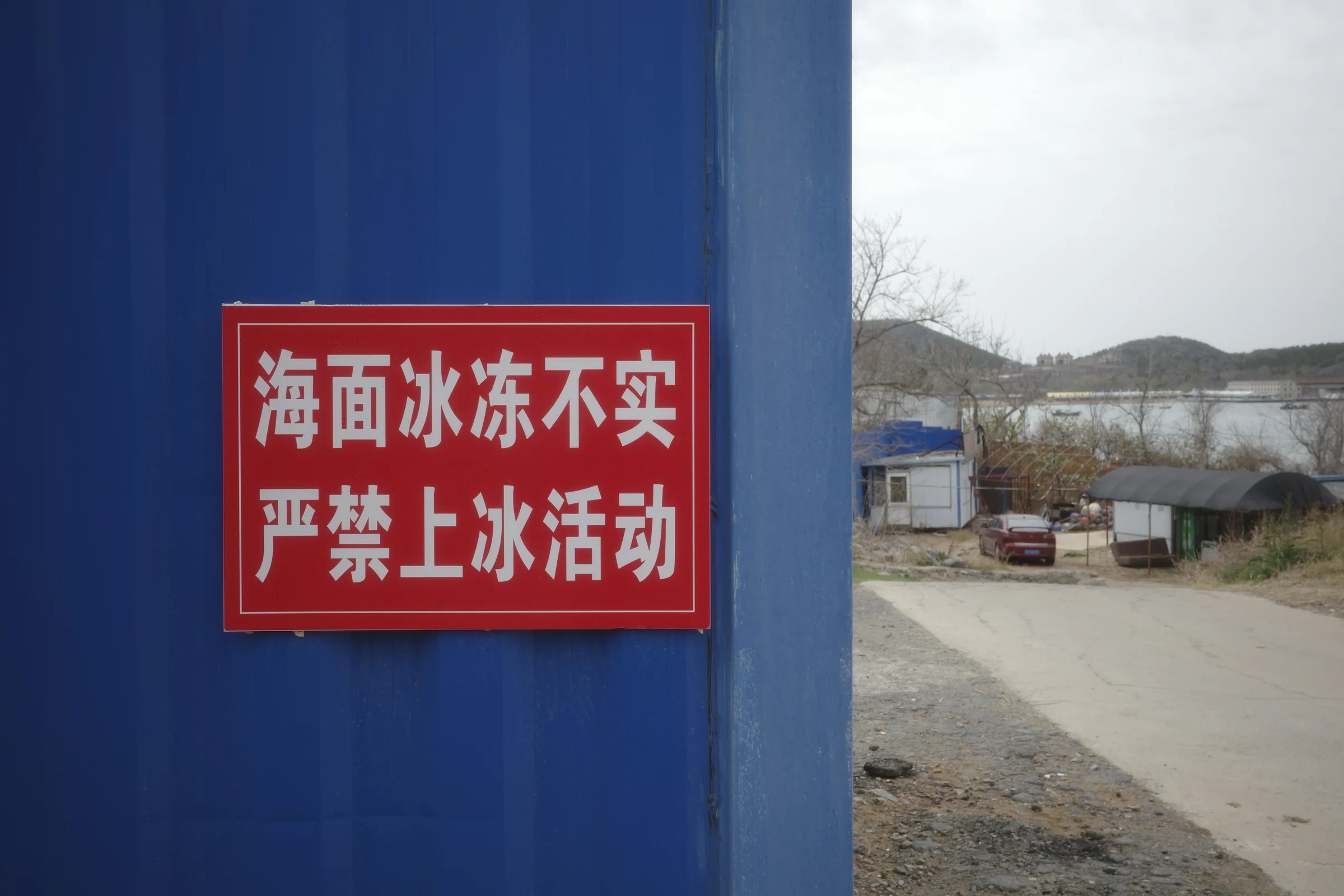 山东沿海蓝色墙面上的海冰安全警示牌